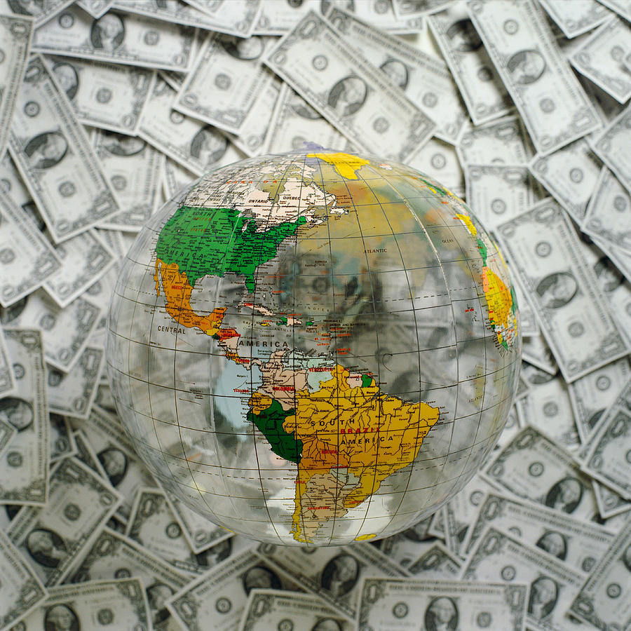 World globe on top of U.S. Dollars. Photograph by Christian Zachariasen