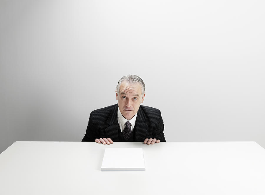 Worried businessman at desk with blank paper  Photograph by Jw Ltd