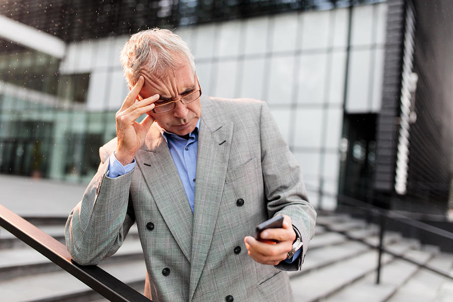 Worried businessman reading a text message on smart phone. Photograph by BraunS