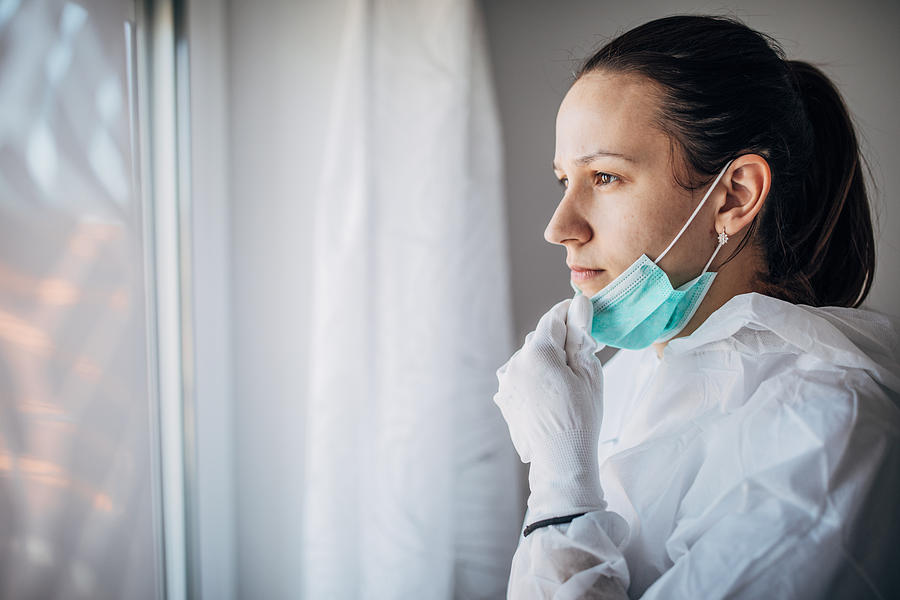 Worried female doctor looking through the hospital window Photograph by South_agency