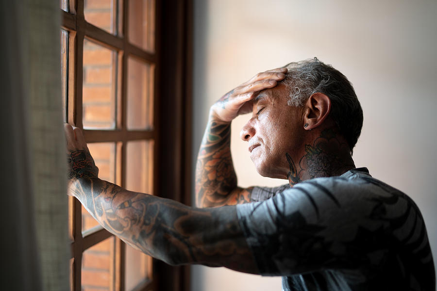 Worried mature man standing at home, close to a window, with hand in the head Photograph by FG Trade