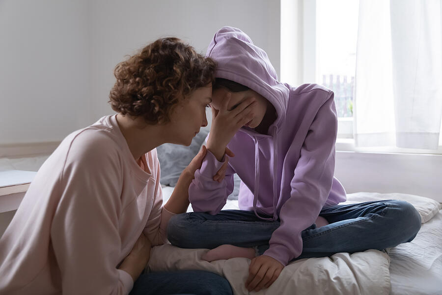 Worried mom comforting depressed teen daughter crying at home Photograph by Fizkes