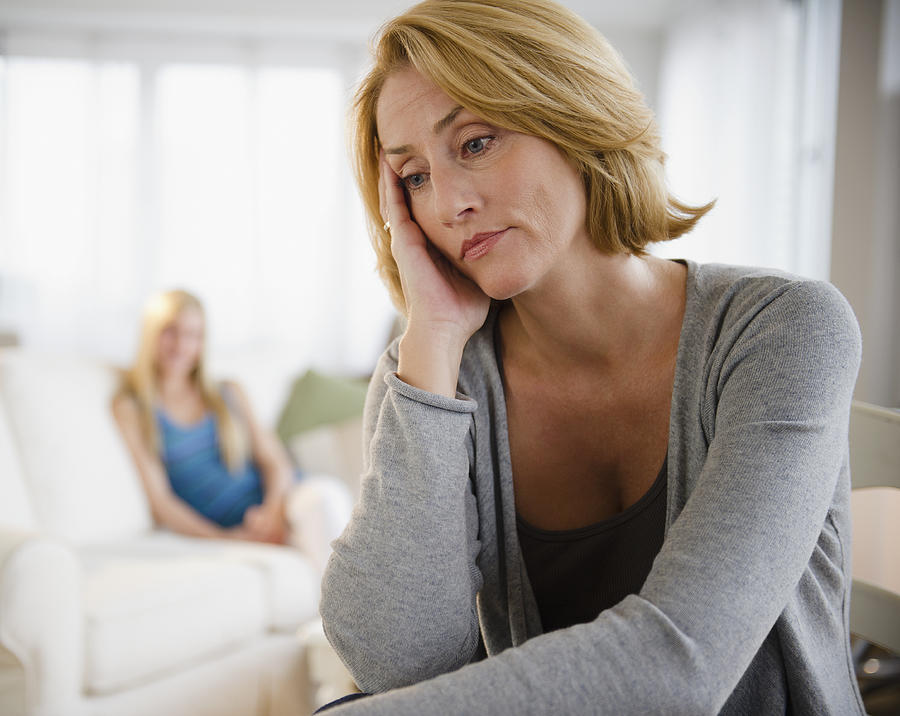 Worried mother, teenage daughter in background Photograph by Jamie Grill