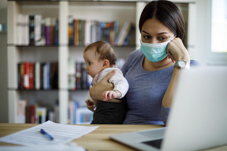 Worried mother with face protective mask working from home Photograph by Damircudic