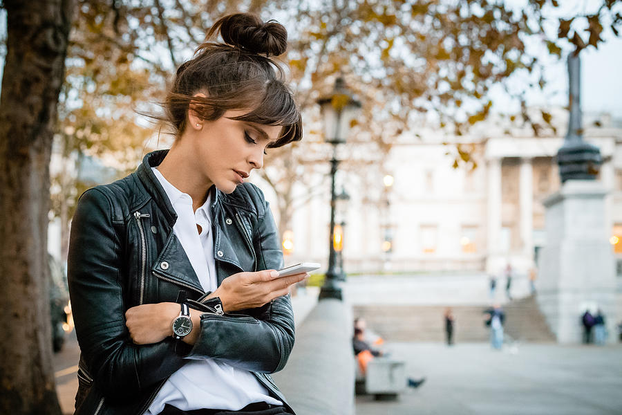 Worried woman using smart phone at Trafalgar Square in London, autumn season Photograph by Izusek