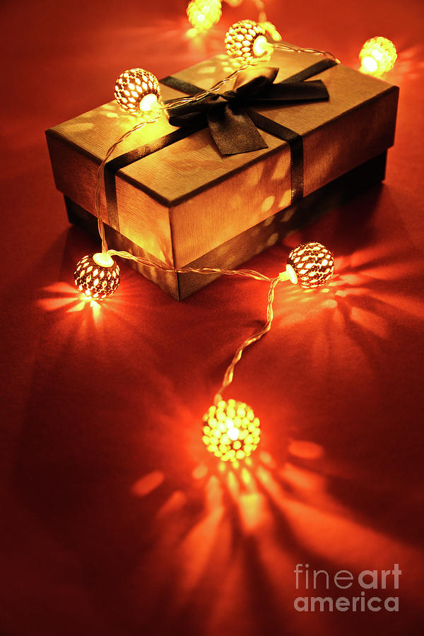 Wrapped gift under glowing Christmas lights Photograph by Mendelex Photography