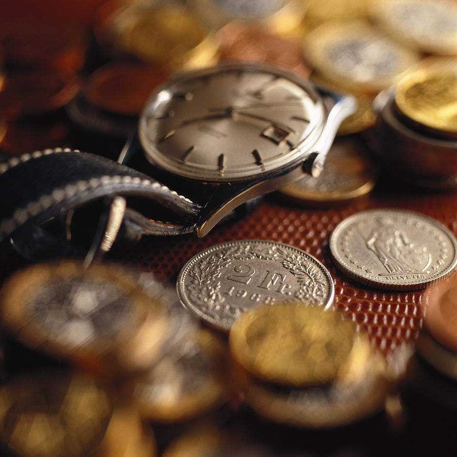 Wristwatch on top of assorted coins. Photograph by Christian Zachariasen