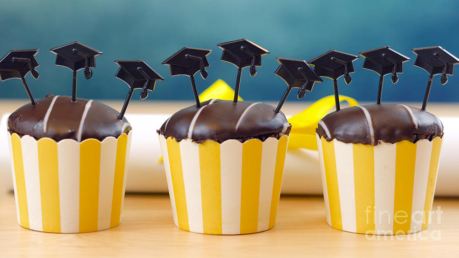 Yellow and blue theme graduation party cupcakes with cap hats toppers. Photograph by Milleflore Images