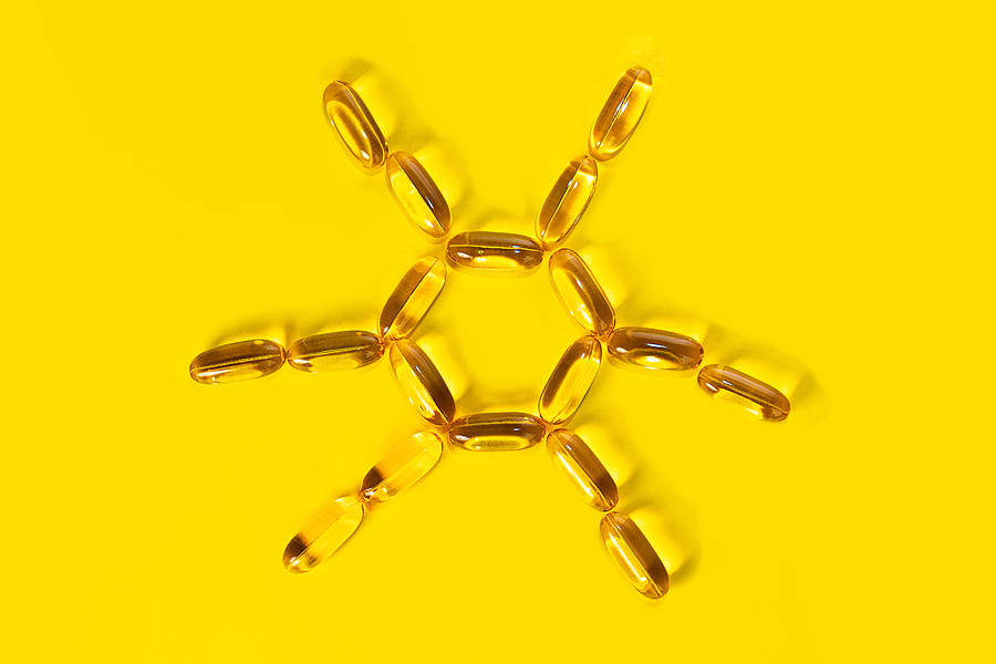 Yellow pills forming shape to sun. Capsules with Omega 3. Photograph by Iryna Veklich