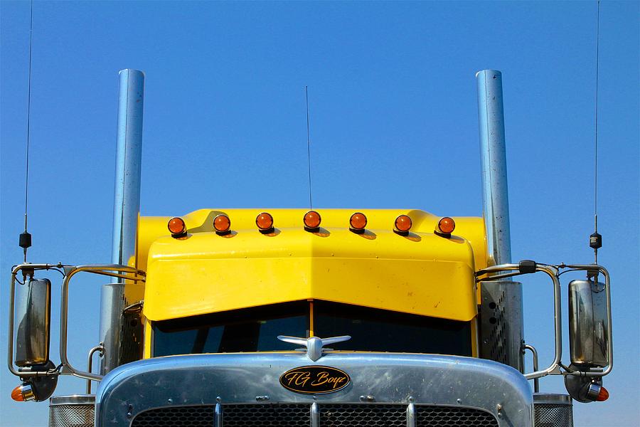Yellow semi-truck against blue sky Photograph by JanaShea