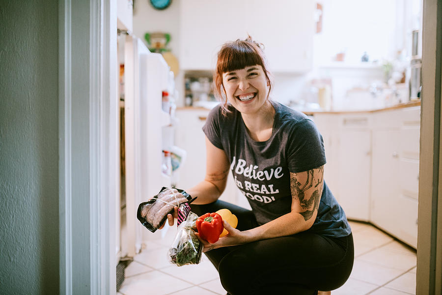 Young Adult Woman Taking Food From Refrigerator Photograph by RyanJLane