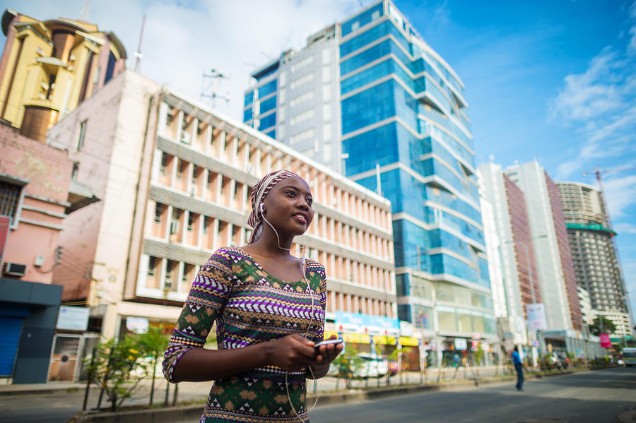 Young African Girl listening to music on earphones from Mobile Phone in the city centre Photograph by Wilpunt