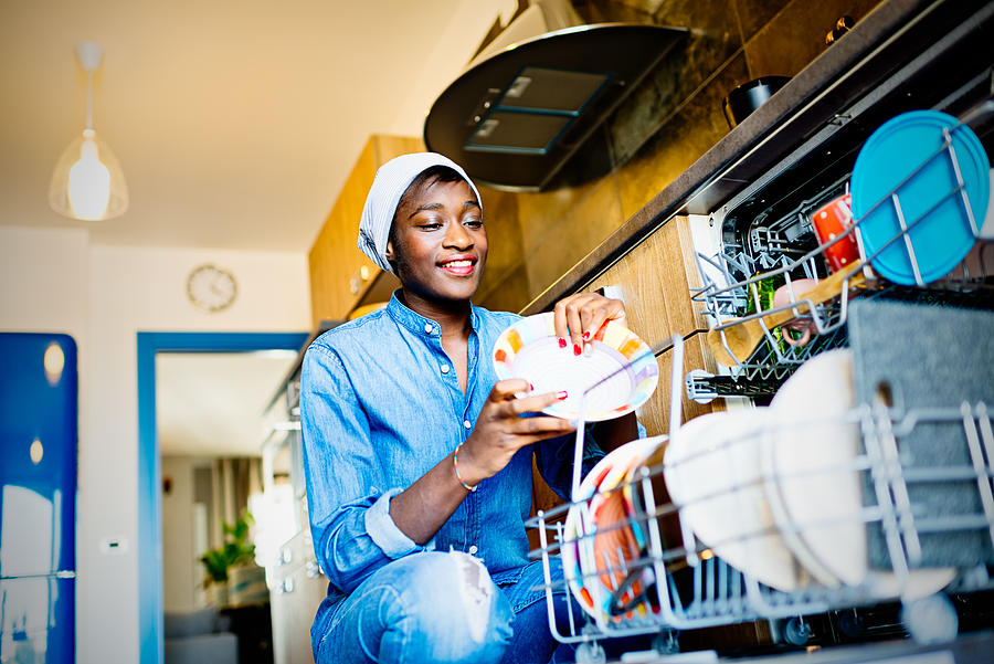 Young African woman using dishwasher in domestic kitchen Photograph by LaraBelova