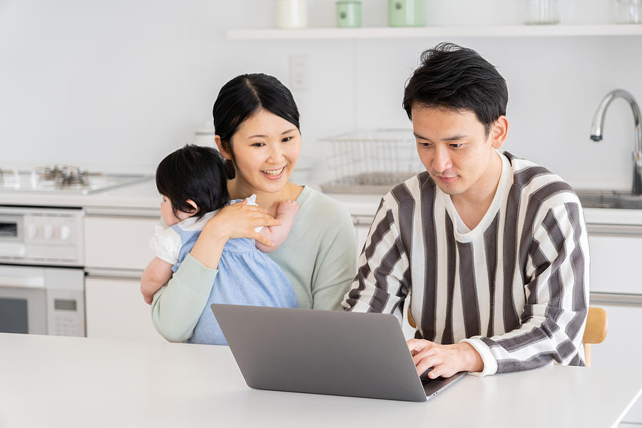 Young Asian Family Using Laptop In Kitchen Photograph by Itakayuki