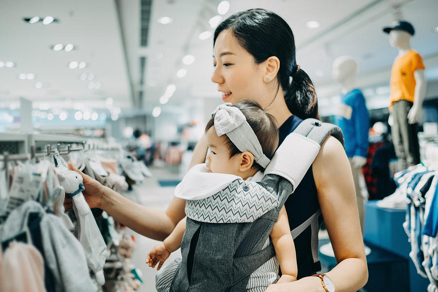 Young Asian mother and baby girl shopping and looking at soft toys in a shop Photograph by D3sign