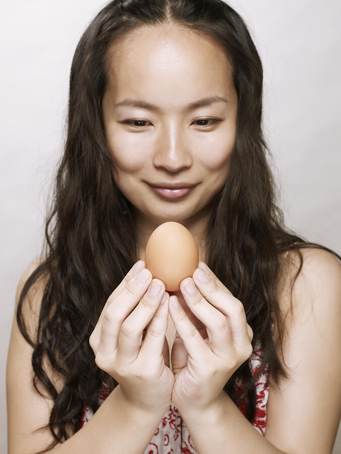 Young asian woman holding an egg Photograph by Ballyscanlon