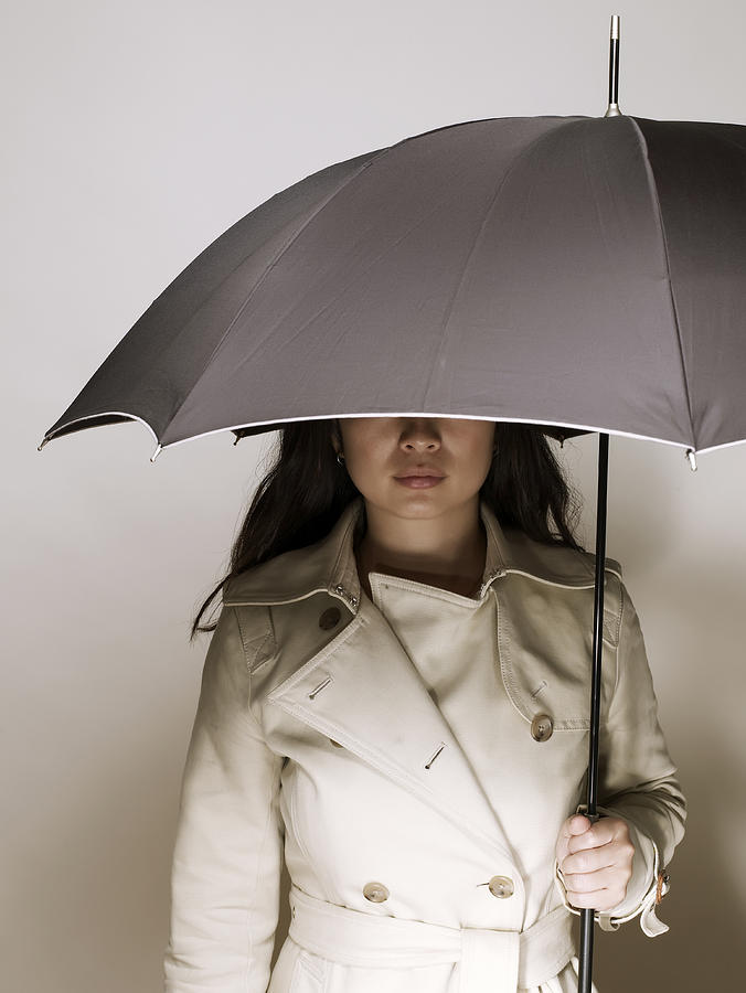 Young asian woman in raincoat, holding umbrella Photograph by Ballyscanlon