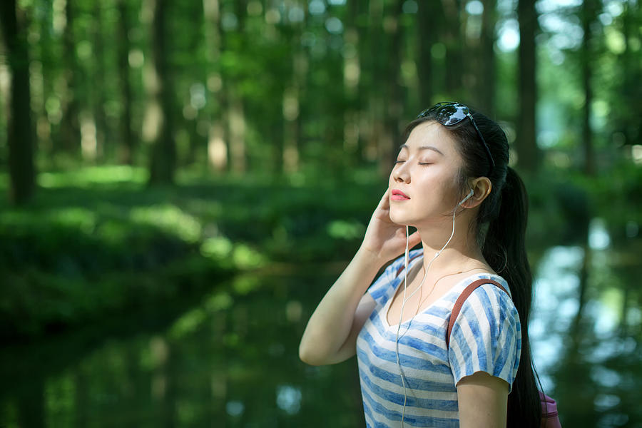 Young asian woman listening to music in forest,with eyes closed Photograph by Xia Yuan