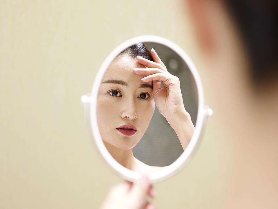 Young Asian Woman Looking At Self In Mirror Photograph by Imtmphoto