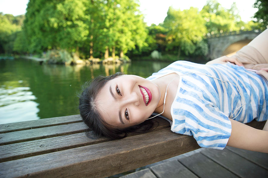 Young asian woman lying on pier above lake,listening to music Photograph by Xia Yuan