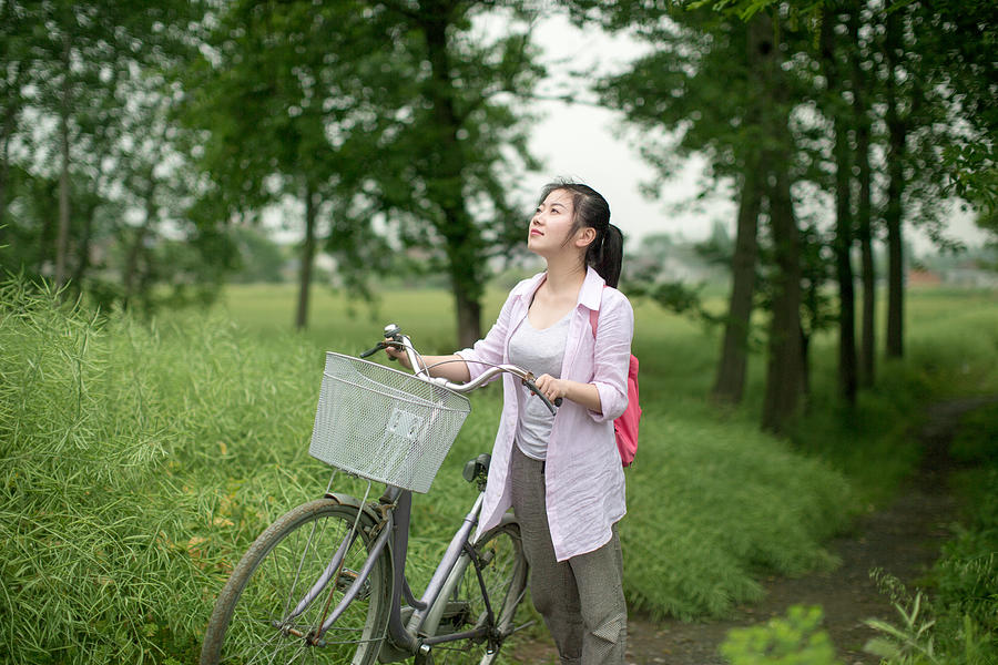 Young asian woman with bike on the country lane Photograph by Xia Yuan