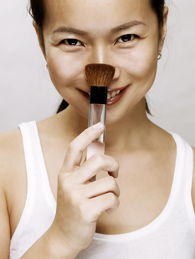 Young Asian Woman With Makeup Brush, Smiling Photograph by Ballyscanlon