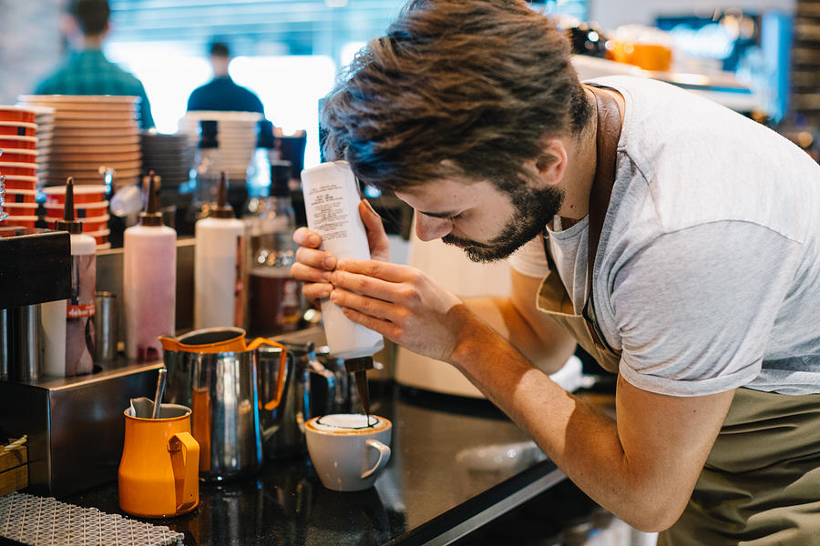 Young Barista Pouring Latte Art with Chocolate Sauce Photograph by Serts