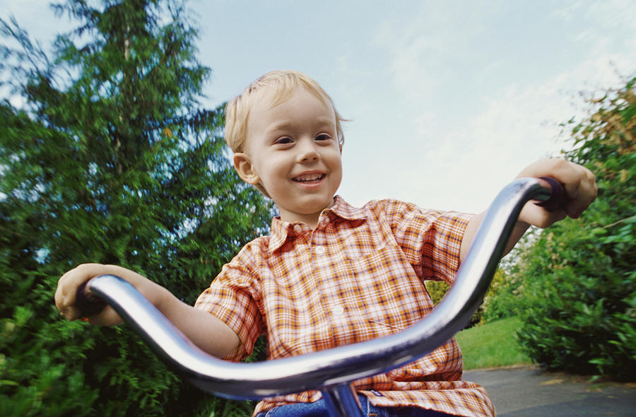 Young Blond Boy Riding a Tricycle in a Park Photograph by Darryl Leniuk