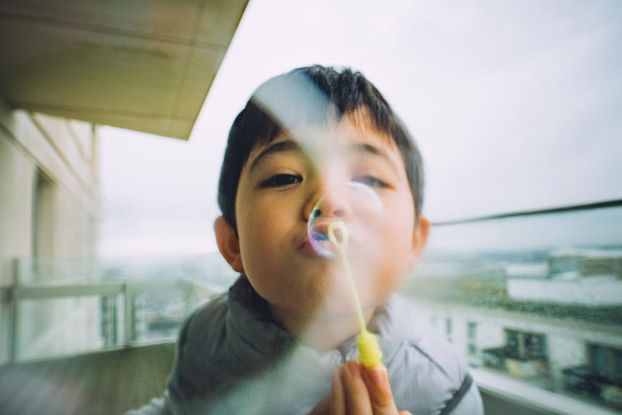 Young boy blowing bubbles Photograph by © Peter Lourenco