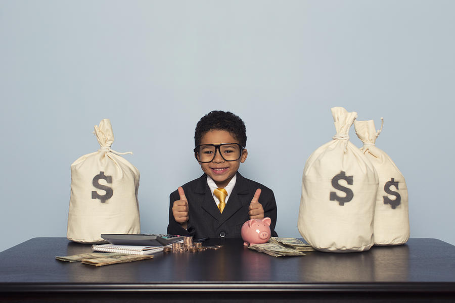 Young Boy Businessman Sits with U.S. Money Savings Photograph by RichVintage