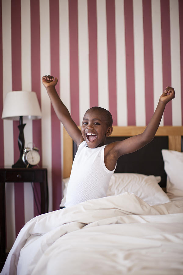 Young boy cheerfully getting out of Bed, Cape Town, South Africa Photograph by BFG Images