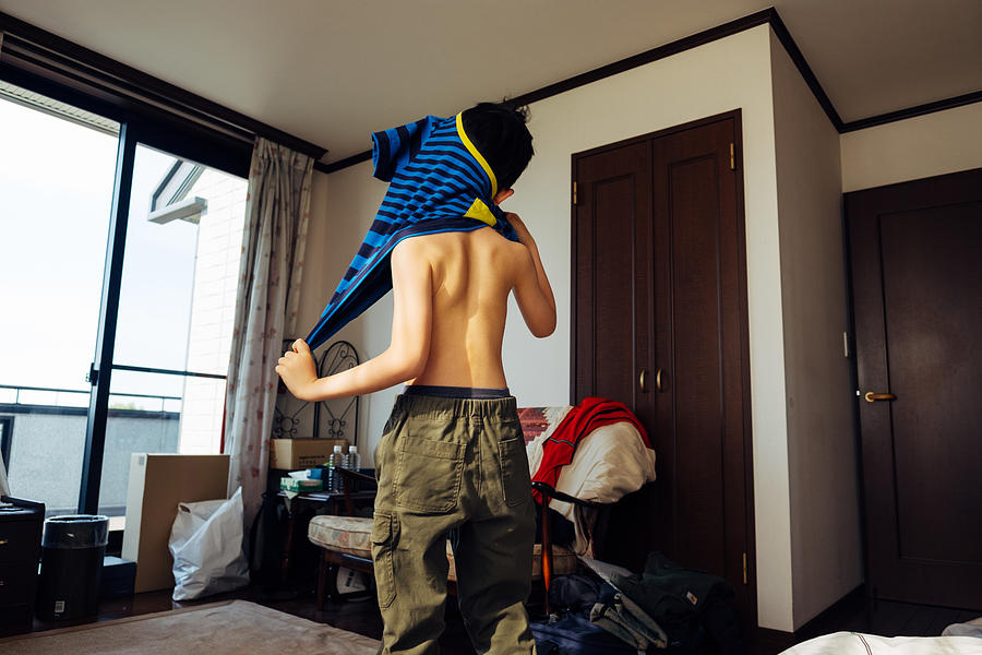 Young boy getting dressed Photograph by © Peter Lourenco