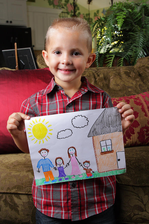 Young boy holding a family drawing at home Photograph by RobMattingley