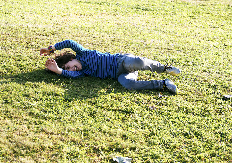 Young boy of six, rolls down a grassy hill Photograph by PhotoStock-Israel
