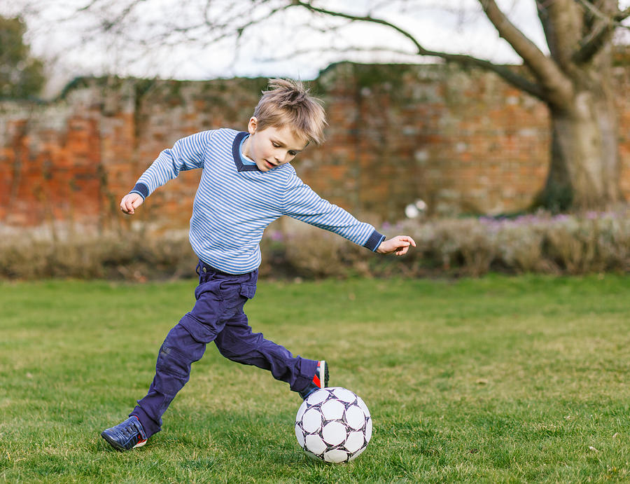 Young boy playing football in the garden Photograph by Deborah Pendell