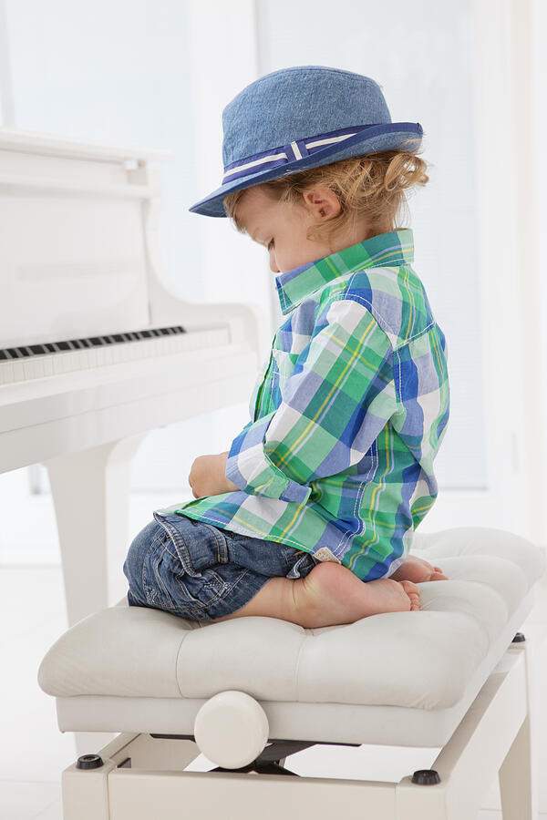 Young boy sitting at a piano Photograph by Juliet White