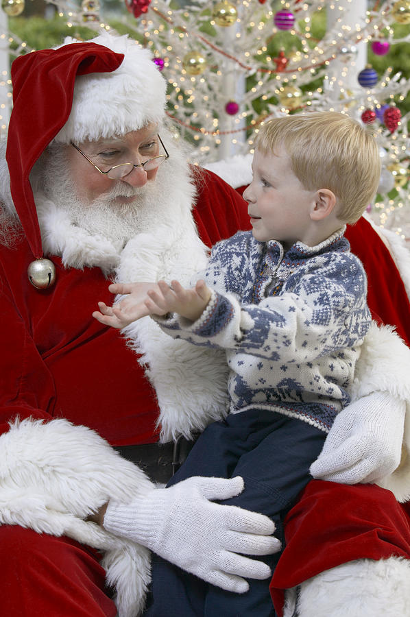 Young Boy Sitting on Father Christmas Lap Photograph by Digital Vision.