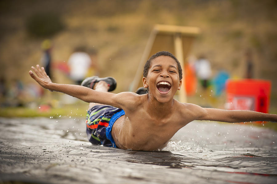 Young Boy Splashing Down On A Slip N Slide Photograph by Stephen Simpson