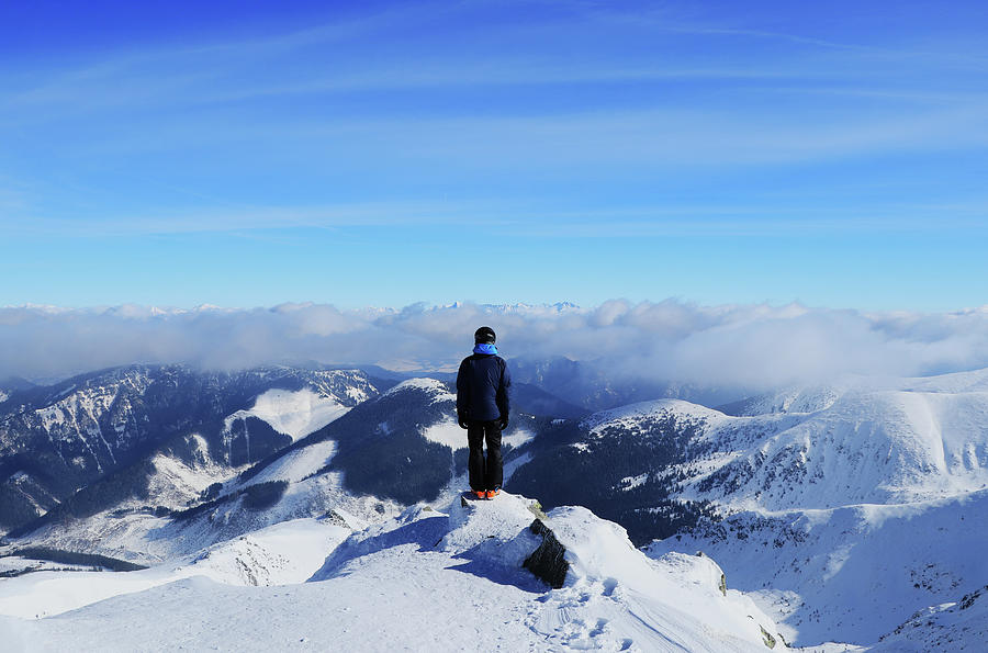 Young Boy Stands On Peak Of Chopok Mountain And Below It Lies The Demanovska Valley And In Far High Tatras. Fairy-tale Panorama With Man In Black Clothes Stands On The Edge Of Mountain Photograph