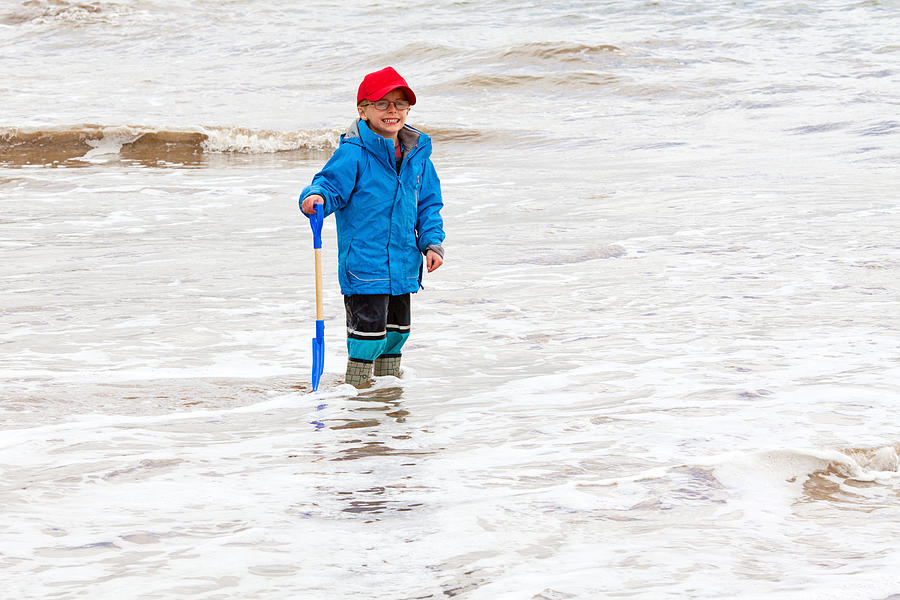 Young boy stood in the sea fully clothed Photograph by Kate Mitchell
