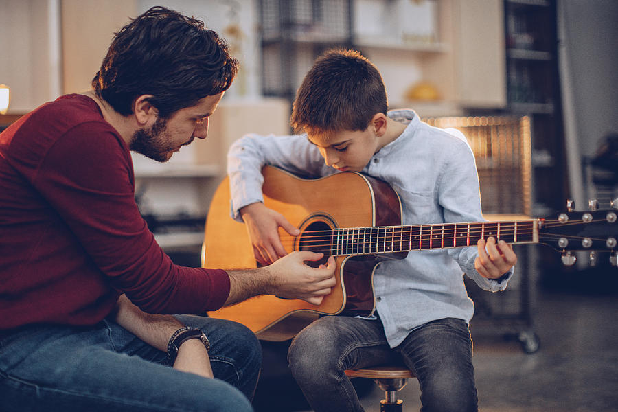 Young boy teaching to play guitar Photograph by South_agency