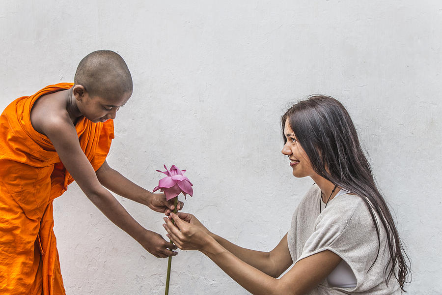 Young Buddist monk gives lotus flower to woman. Photograph by David Trood