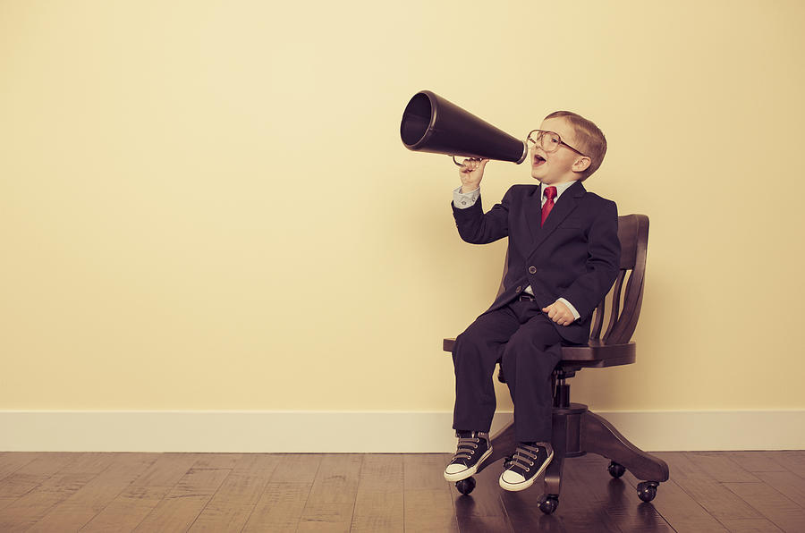 Young Business Boy Sitting in Chair Yelling Through Megaphone Photograph by RichVintage