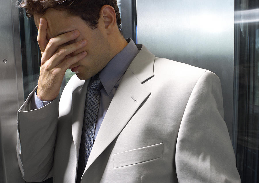 Young businessman covering face. Photograph by Teo Lannie