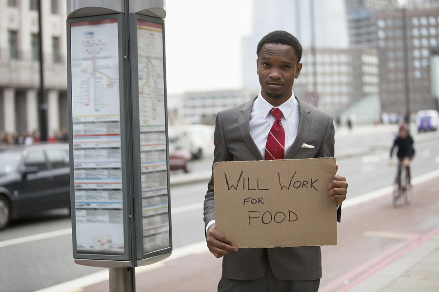 Young businessman holding Will Work for Food sign at street Photograph by Moodboard