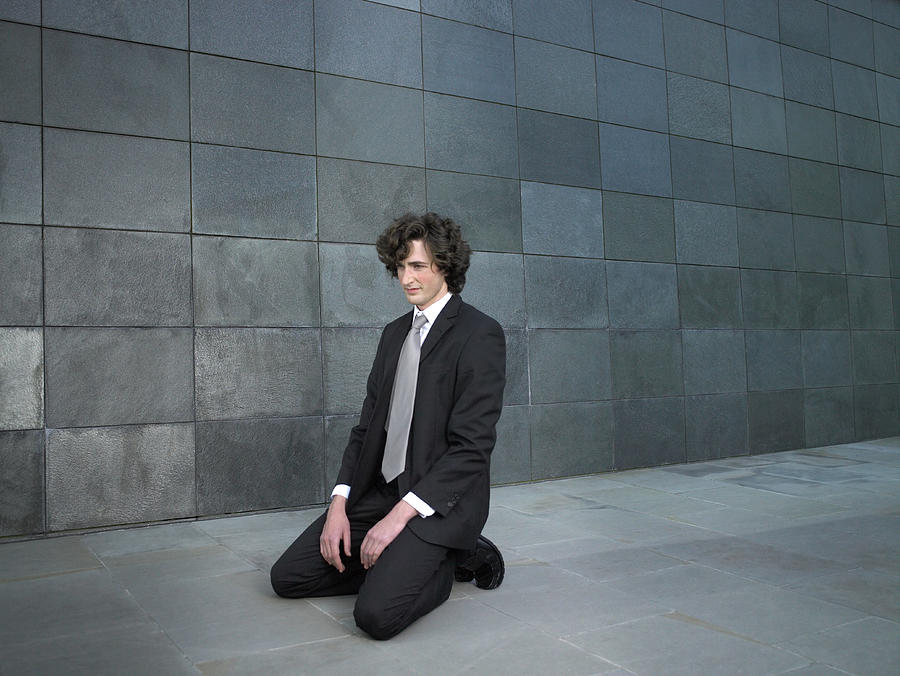 Young businessman kneeling on pavement Photograph by Michael Blann