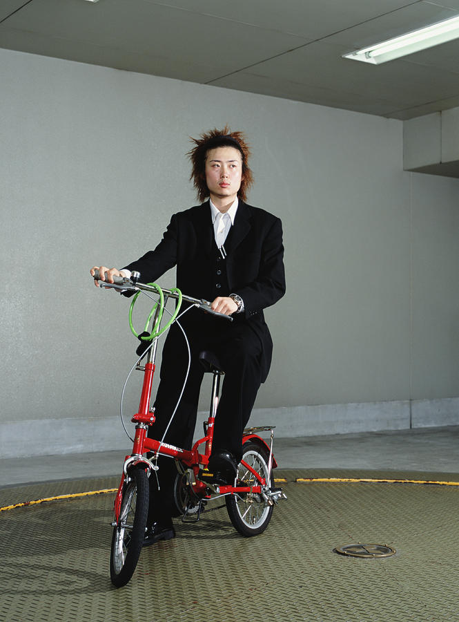 Young businessman on folding bicycle, portrait Photograph by Hans Neleman