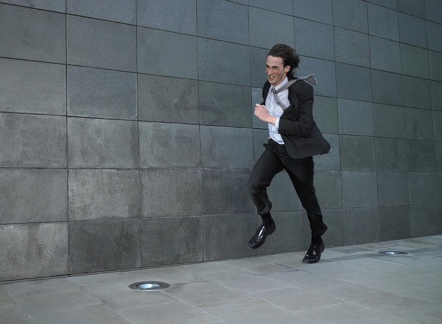 Young businessman running against wind Photograph by Michael Blann