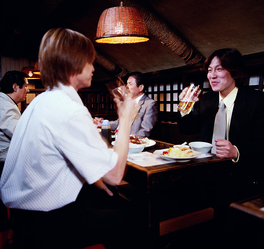 Young businessmen having dinner in restaurant Photograph by Ryan McVay