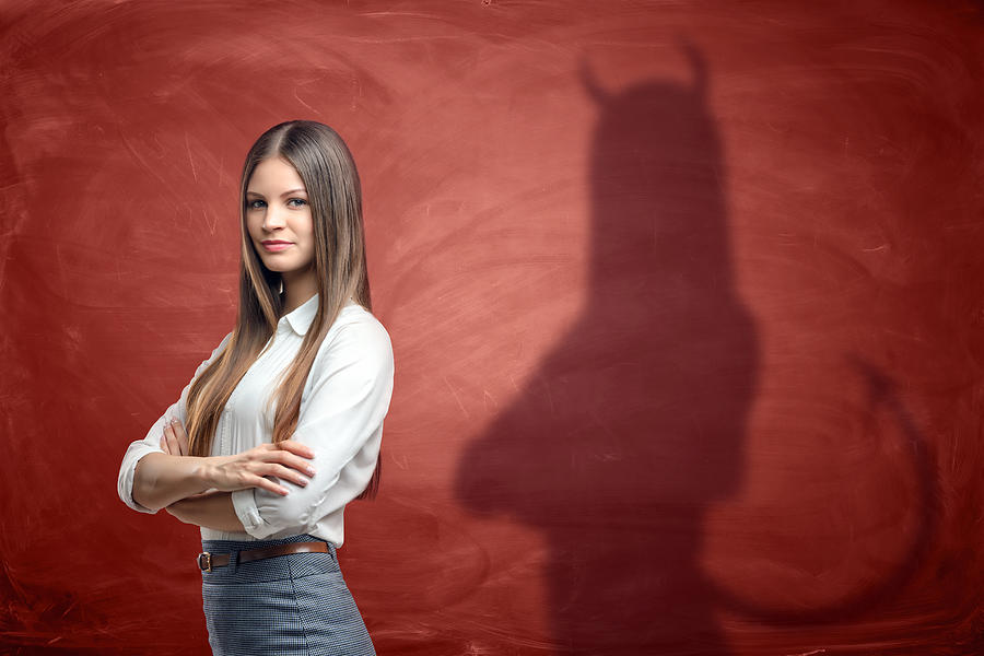 Young businesswoman is casting shadow of devil on rusty orange Photograph by Gearstd